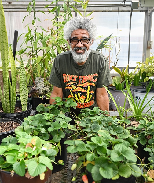 Professor Jose Barbosa standing in front of a row of plants