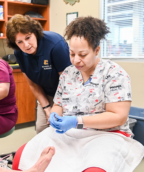Nursing instructor and student serving a patient