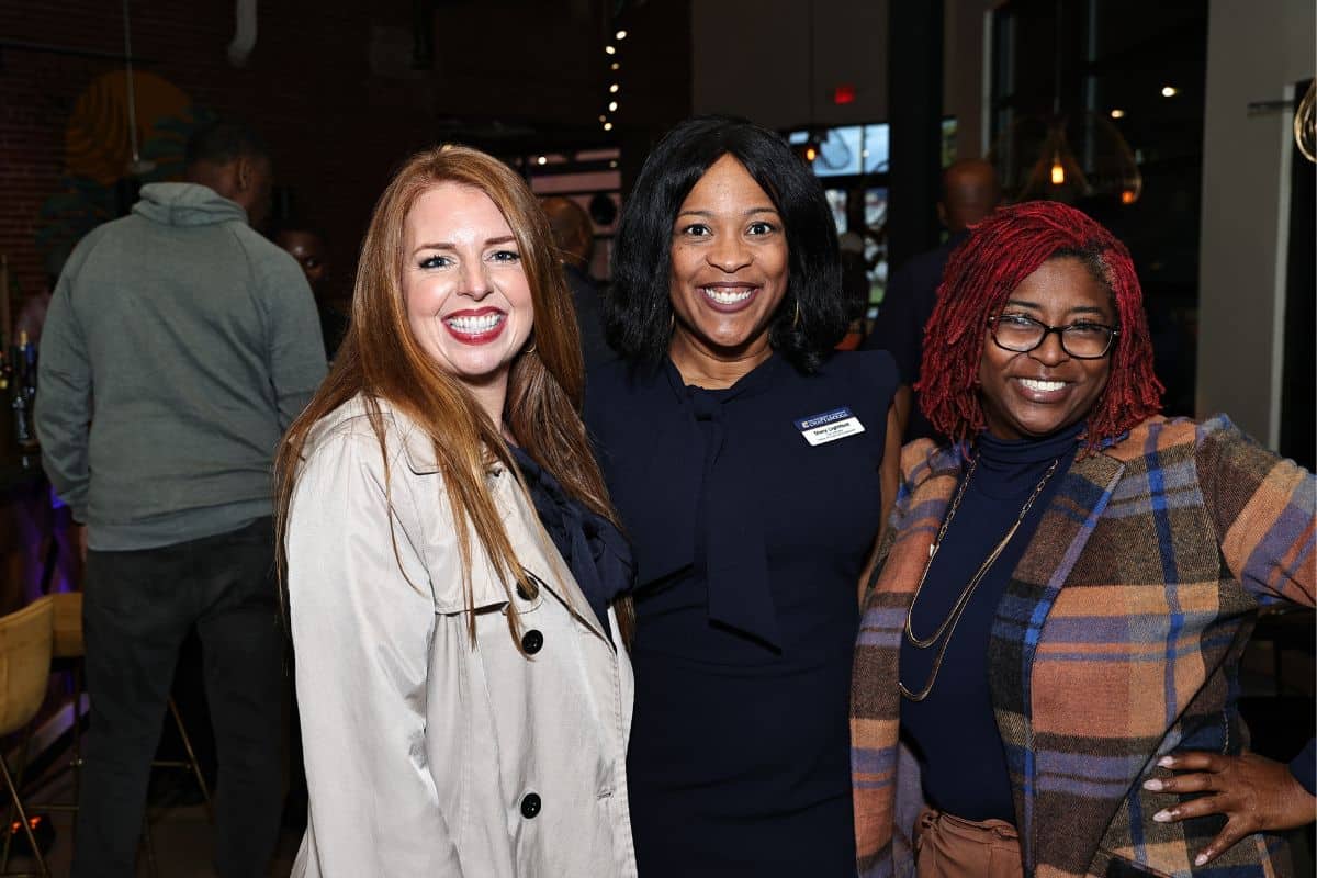 Three people standing together and smiling.