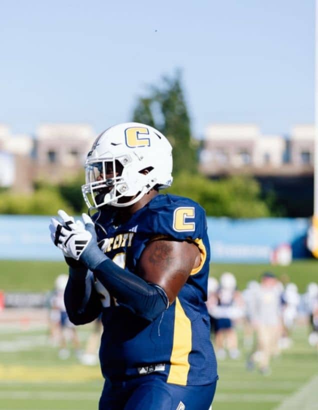 Montrell Henderson walking on a football field.