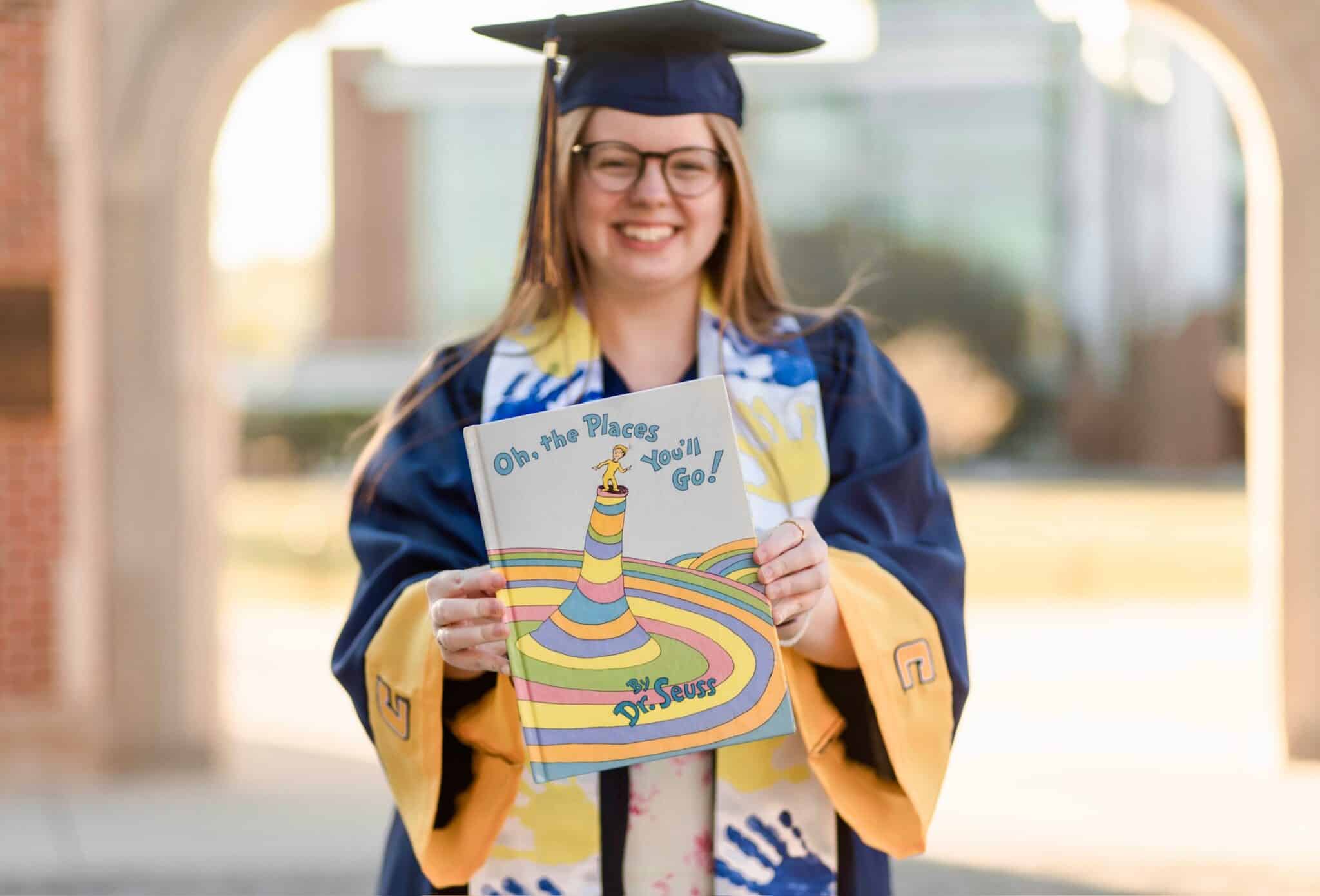 Kendell Wedekind in cap and gown, holding a book.