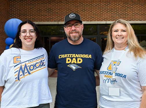 A family standing together, wearing UTC apparel.